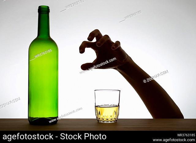 Silhouette of a hand reaching for a glass of wine