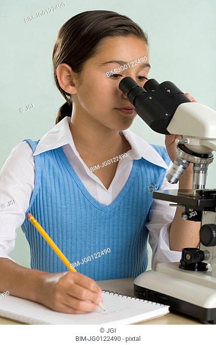 Hispanic girl looking through microscope
