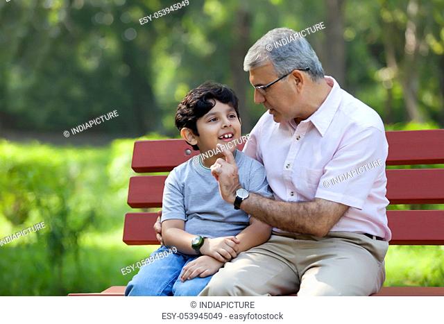 Grandfather and grandson sitting in a park