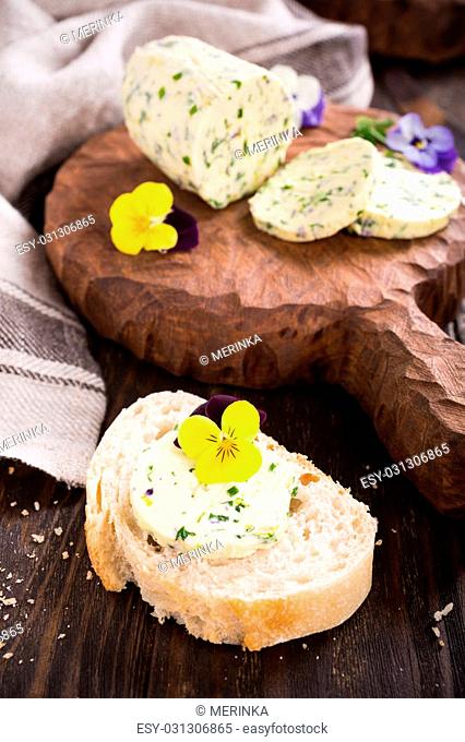 Sandwich with herb and edible flowers butter on wooden background, healthy food