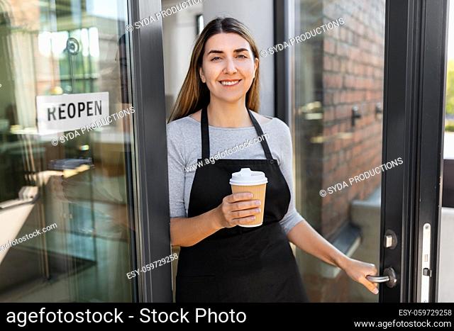 happy woman with coffee and reopen banner on door