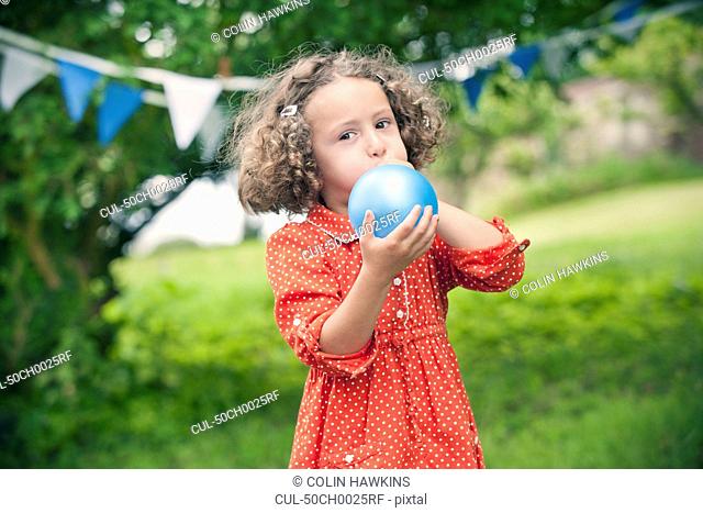 Girl blowing up balloon outdoors