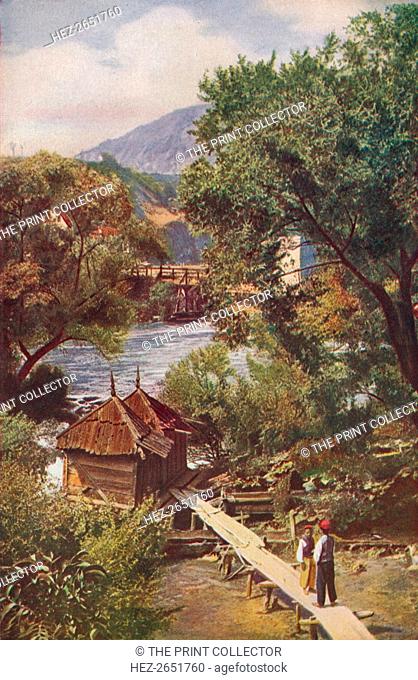 'Bosnia. Where the Pliva skirts the western side of Jajce it turns many a mill-wheel before gathering force above the great waterfall', c1920