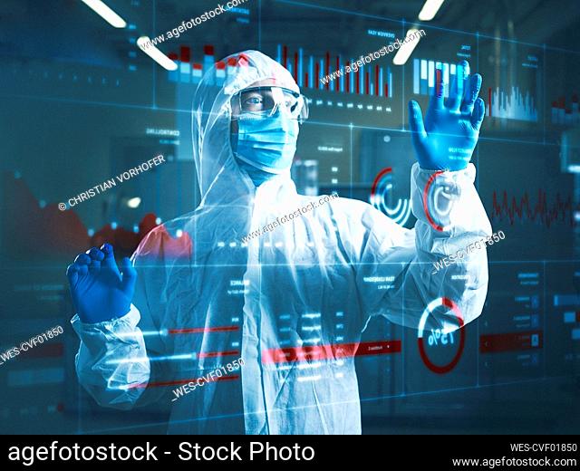 Industrial worker wearing protective workwear using transparent touch screen in clean room