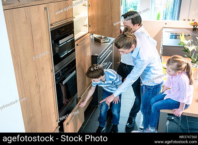 Scene in a kitchen showroom, family shopping for a new model looking at the equipment