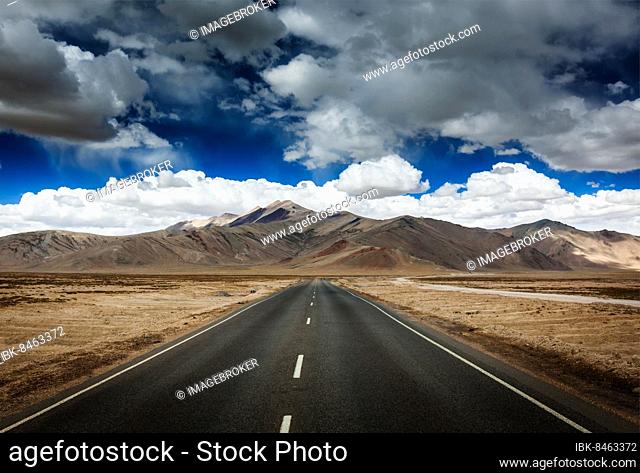 Travel forward concept background, road on plains in Himalayas with mountains and dramatic clouds. Manali-Leh road, Ladakh, Jammu and Kashmir, India, Asia