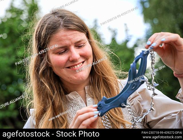 PRODUCTION - 10 July 2023, Bremen: Sarah Winkelmann, expedition adventurer from Bremen, Germany, holds spikes she used during her expedition in her garden