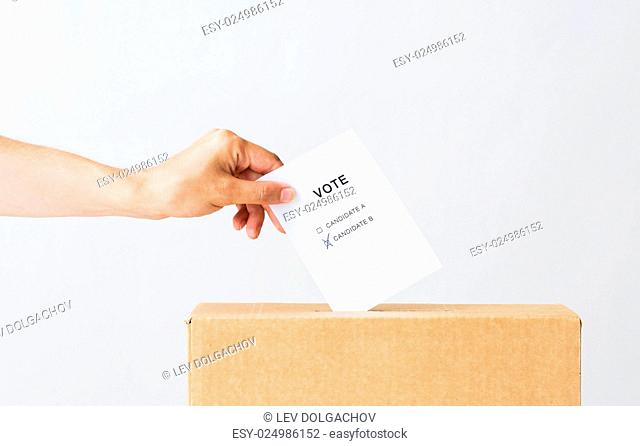 voting, civil rights and people concept - male hand putting vote with two candidates into ballot box on election