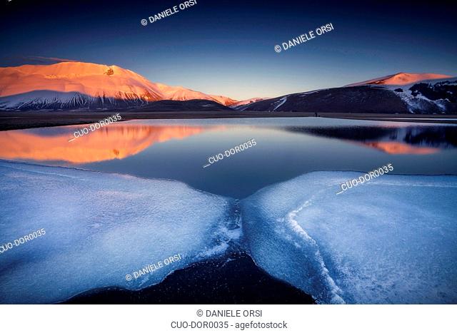 Beautiful landscape in Castelluccio di Norcia during a frozen sunset on Mount Redentore reflected in the lake, Umbria, Italy, Europe