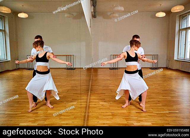 beautiful couple dancing tango. young woman in black and white dress and man in sport clothes practicing in dancing studio mirror room. copy space