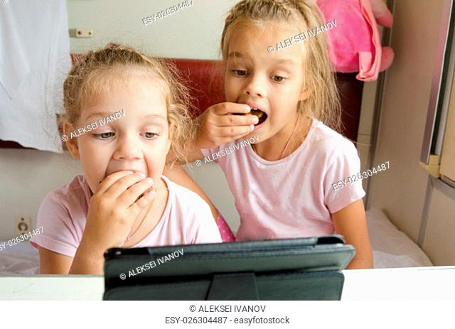 Two girls sisters sitting in the train watching cartoon Tablet PC