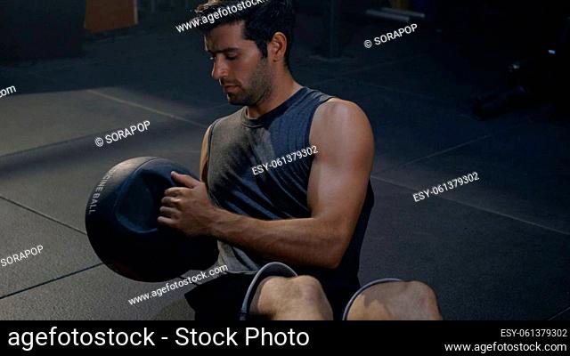 Young muscular athletic man doing training abdomen exercises working out with a medicine ball in fitness gym, strength workout healthy lifestyle sport concept