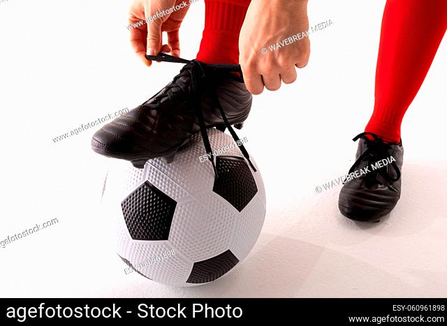 Close-up of caucasian young female player tying shoe lace while standing with foot on soccer ball