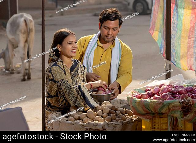 A RURAL COUPLE BUYING VEGETABLES TOGETHER IN A MARKET