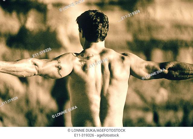 23 year old man's back as he flexes, outdoors