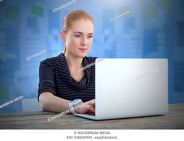 Businesswoman working on laptop with blue background