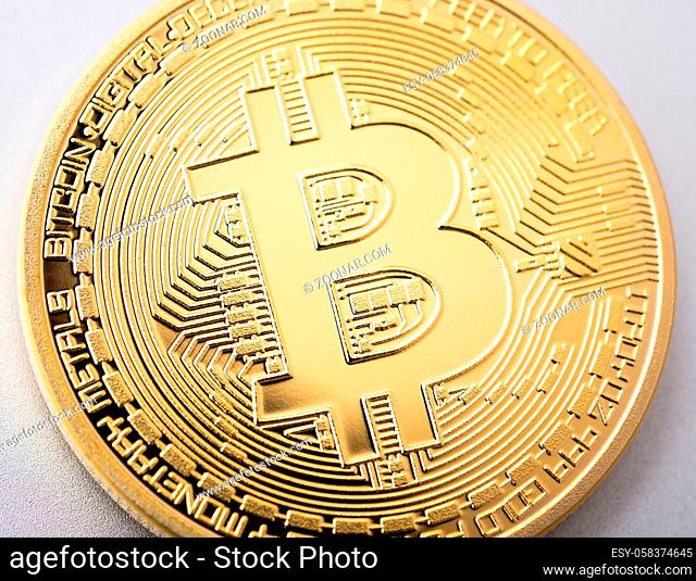 Physical cryptocurrency golden Bitcoin coin on brushed aluminium background