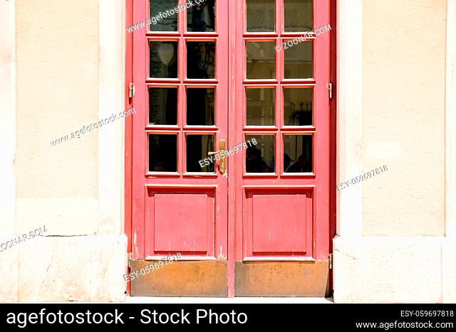 Old red doors with windows in the door with white walls. High quality photo