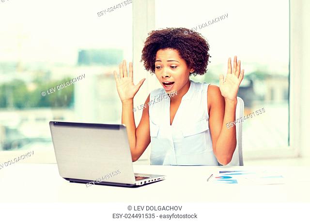 education, business, fail and technology concept - african american businesswoman or student with laptop computer and papers at office