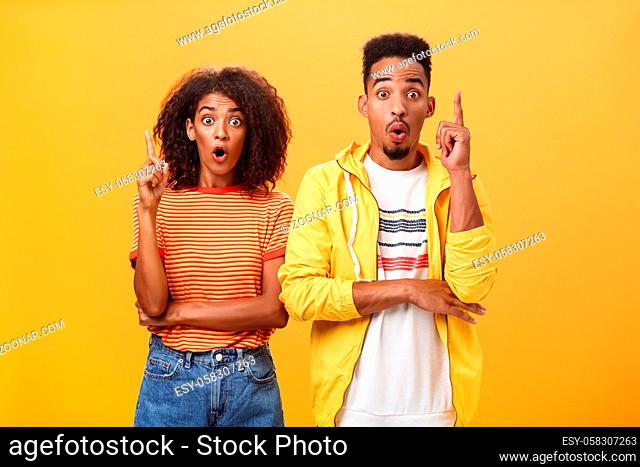 The both got perfect idea at same time. Amazed and excited creative charismatic african american man and woman raising index fingers in eureka gesture opening...