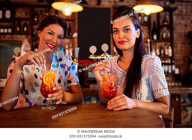 Portrait of two young women having cocktail drinks