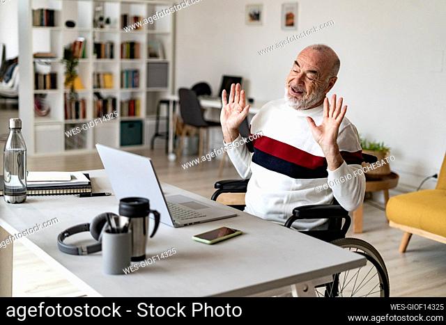 Disabled businessman gesturing and talking on video call using laptop at home office