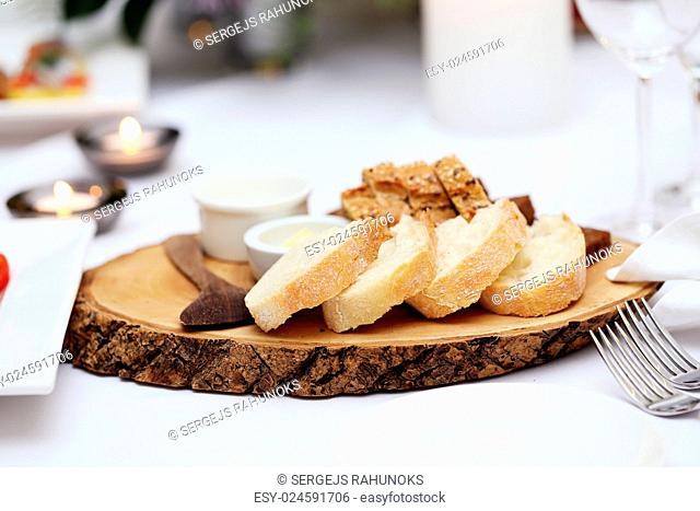 Two different types of bread with sour cream and a wooden spoon lying on a wooden plate