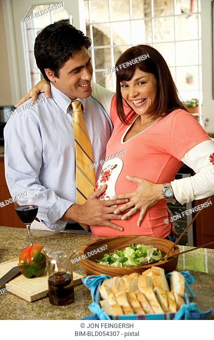 Pregnant Hispanic couple hugging