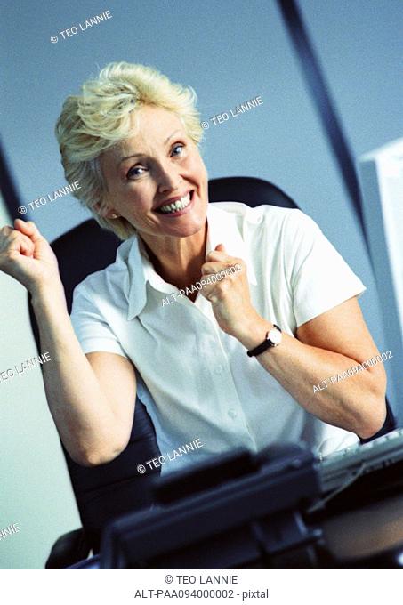 Businesswoman raising fists and smiling, portrait