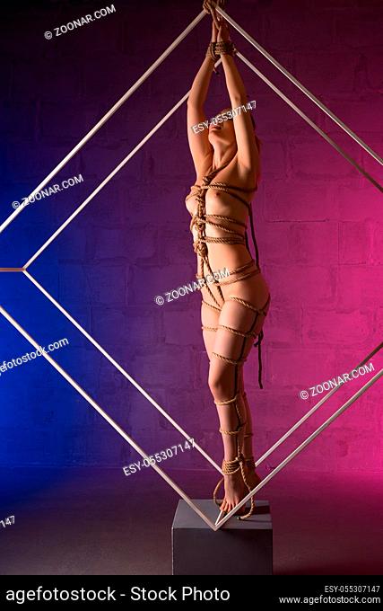 Nude girl tied up in shibari style full-length shot in color lights