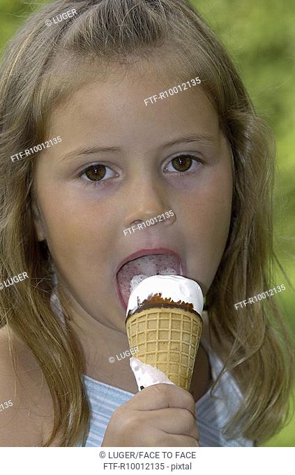 Little blond girl eating an ice cream
