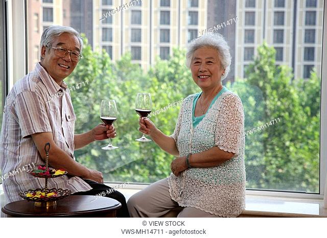 Mature couple drinking red wine at table