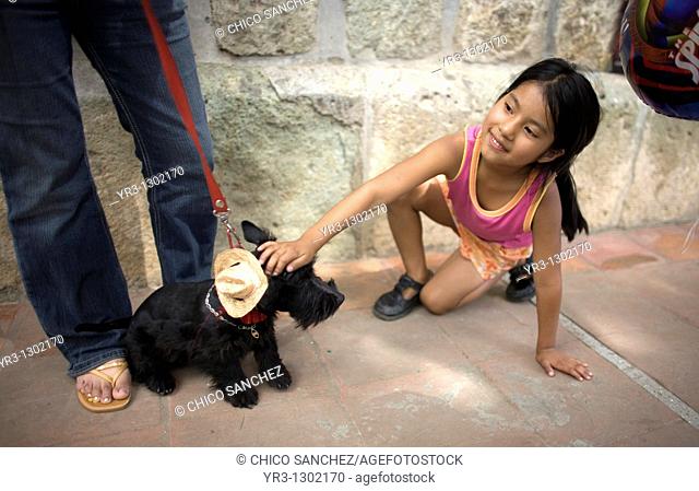 A girl plays with a dog who wears a hat during the Blessing of the Animals celebration in Oaxaca, Mexico, August 31, 2008  La Merced Catholic church celebrates...