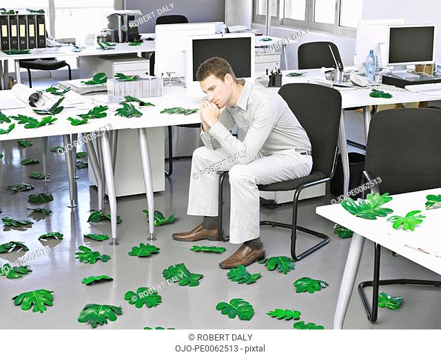 Businessman in modern office surrounded by leaves