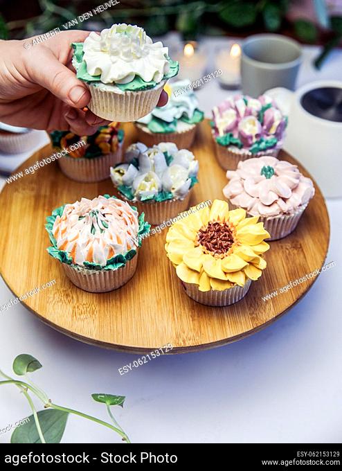 Woman holding a tasty fresh cupcake decorated with flower icing on beautiful wedding party table, high tea, Mothers day Holiday sugar