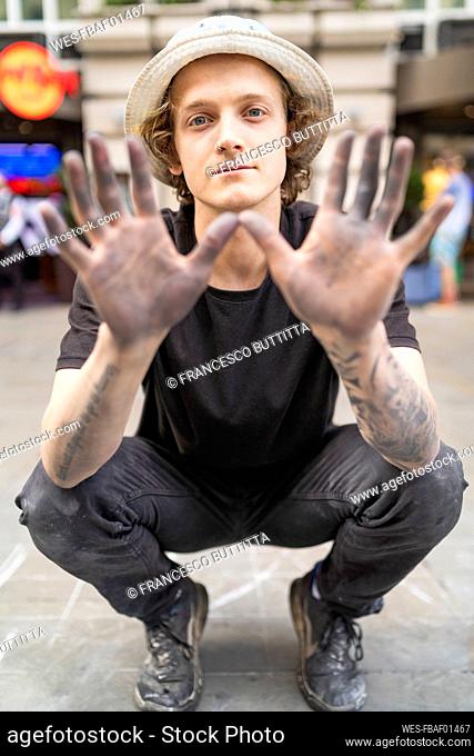 Street art, pavement artist showing his dirty hands