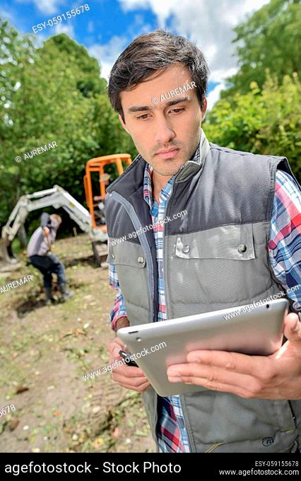 Man stood in garden, holding tablet
