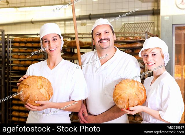 Baker standing with his team in bakery with freshly baked bread