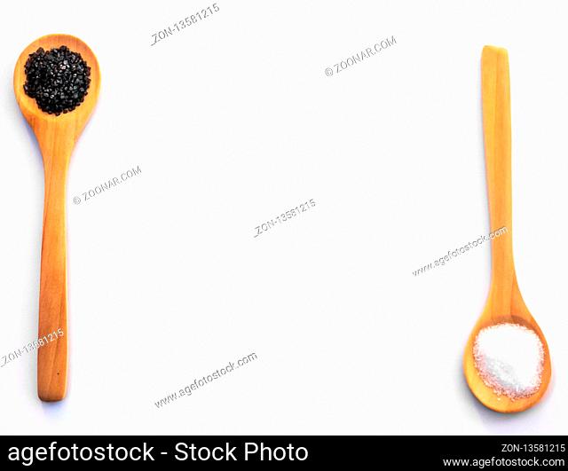 Wooden spoons with marine common salt and black hawaii salt on a white background