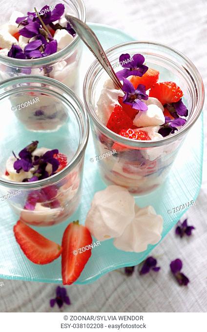summer dessert with strawberries, vanilla cream, meringue and violet