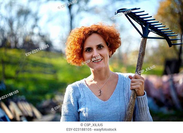 Farmer lady raking, cleaning the garden