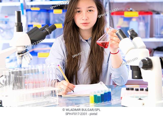 MODEL RELEASED. Girl holding chemical flask in laboratory