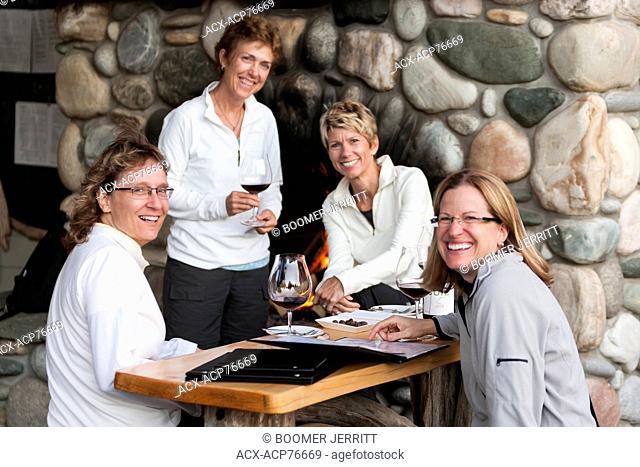 Four friends enjoy a glass of wine and conversation while waiting for a table at Sobo's, an upscale eatery in Tofino. Tofino, Vancouver Island, British Columbia