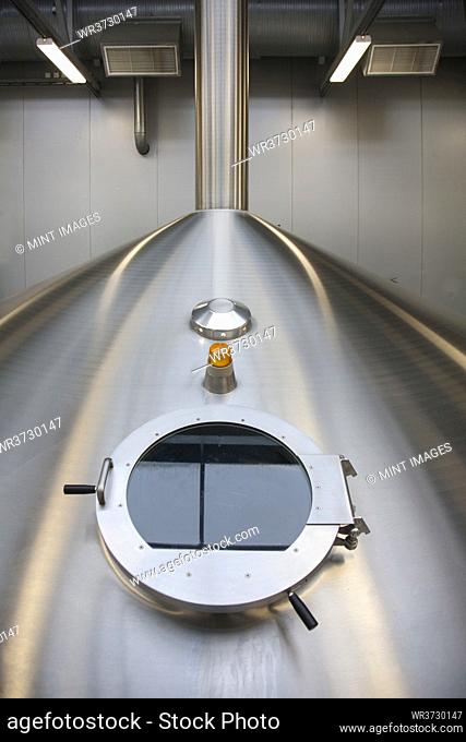 Interior of brewery, large steel storage tanks for brewing beer, inspection hatch