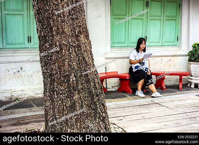 A girl is reading a book in the street. Bangkok. Thailand