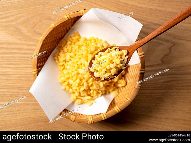 Tenkasu served in a colander placed on a wooden background with a wooden spoon. Image of Japanese food. View from above