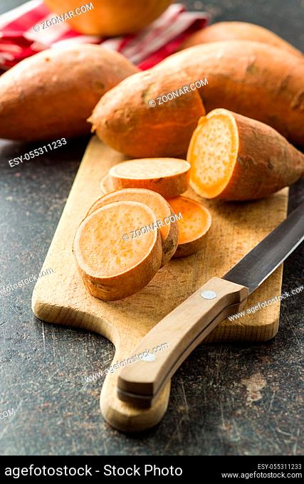 The sweet potatoes on cutting board on old kitchen table
