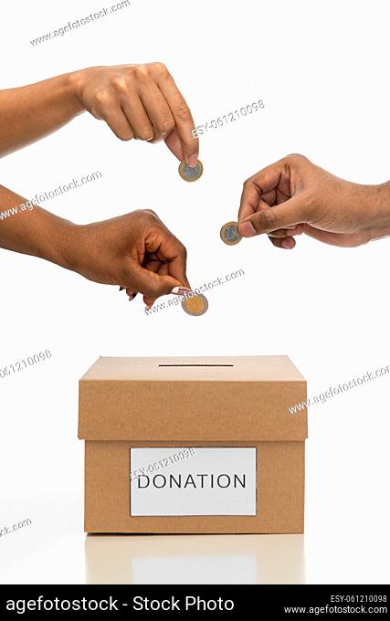 close up of hands putting coins into donation box