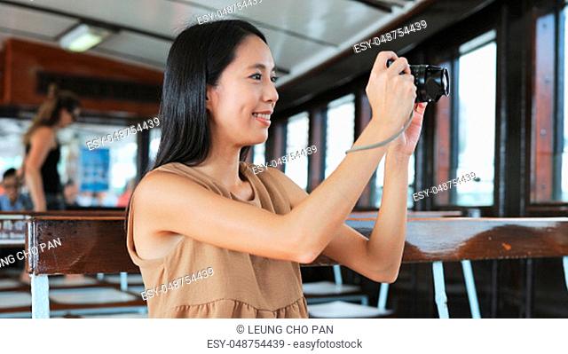 Traveler taking photo with digital camera on ferry in Hong Kong city