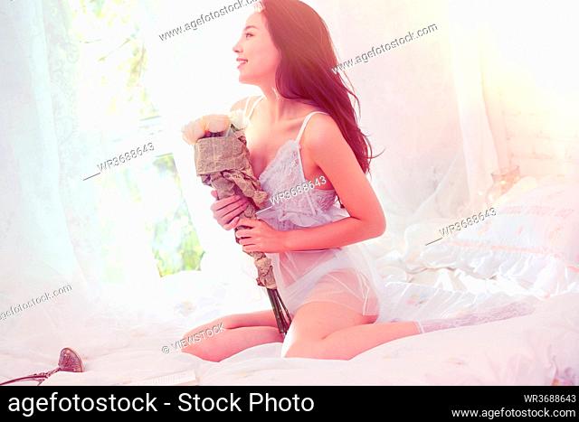 A beautiful young woman sitting on the bed with a bouquet of flowers
